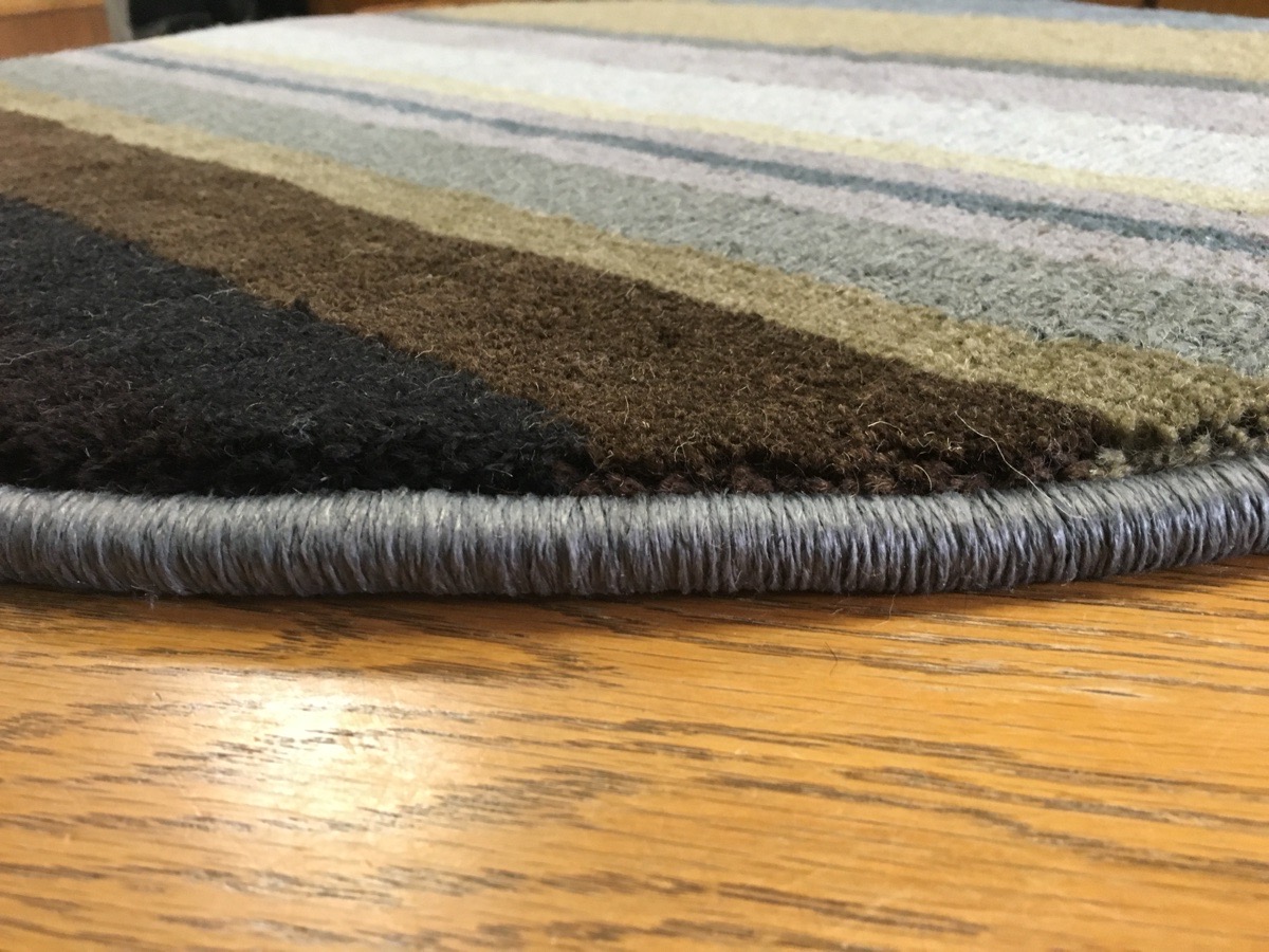 Serging close-up &mdash; silver wrapped-yarn edge on a multi-stripe wool rug