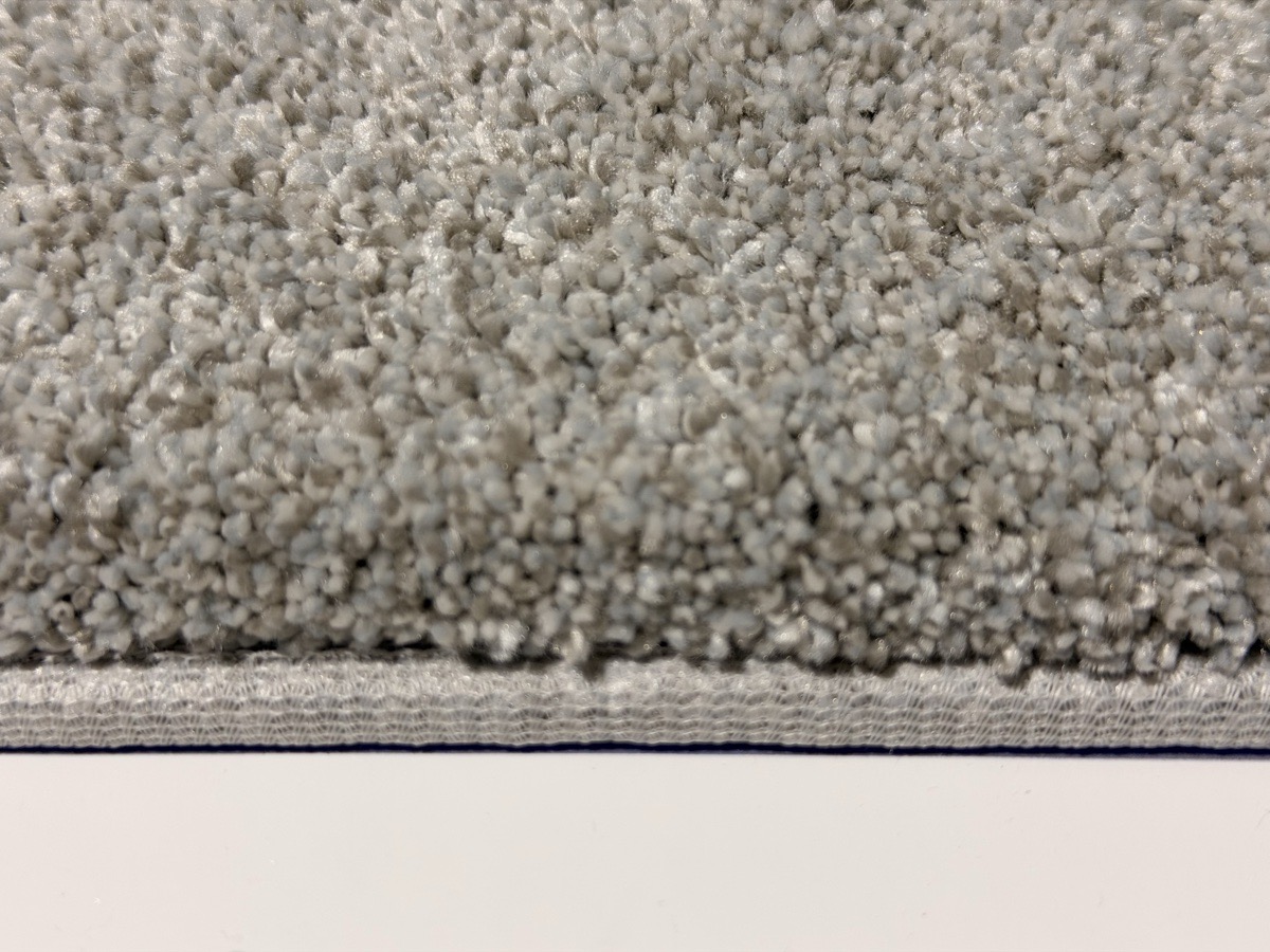 Standard 7/8 inch binding close-up &mdash; flat cream tape on gray plush carpet