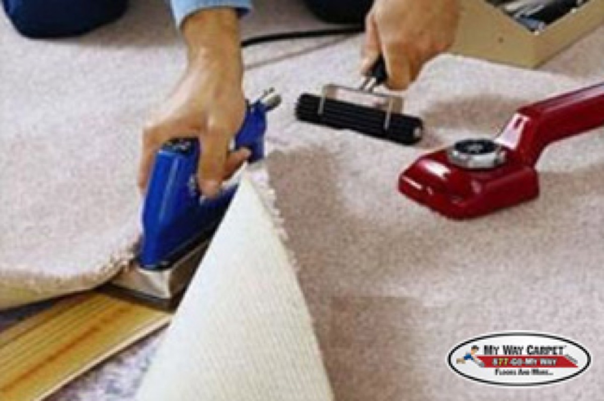 MWC installer using a blue seam iron with a power stretcher nearby